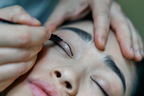 Free A close-up image of a makeup artist applying eyeliner to a woman's eyelid with precision. Stock Photo