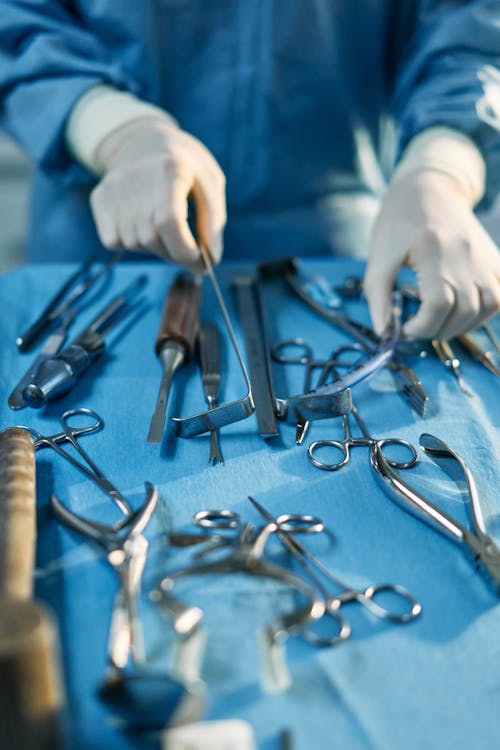 Person Holding Silver Medical Tools