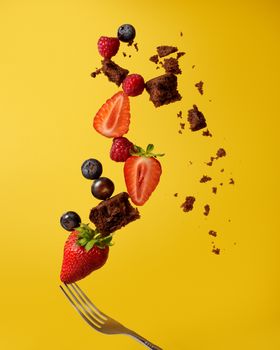 Dynamic food composition with fruits and brownie pieces levitating against a vibrant yellow backdrop.