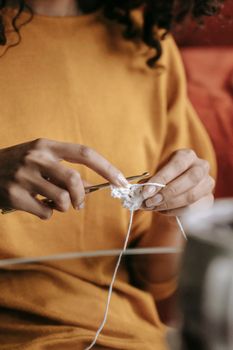 A close-up of a woman crocheting with focus on her hands and yarn, highlighting her hobby and craftsmanship.