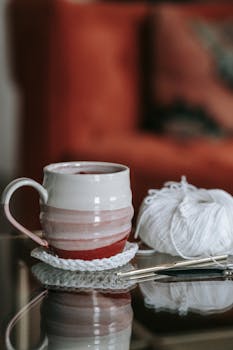 Warm and inviting scene of a ceramic mug and crochet yarn, perfect for a relaxing day indoors.