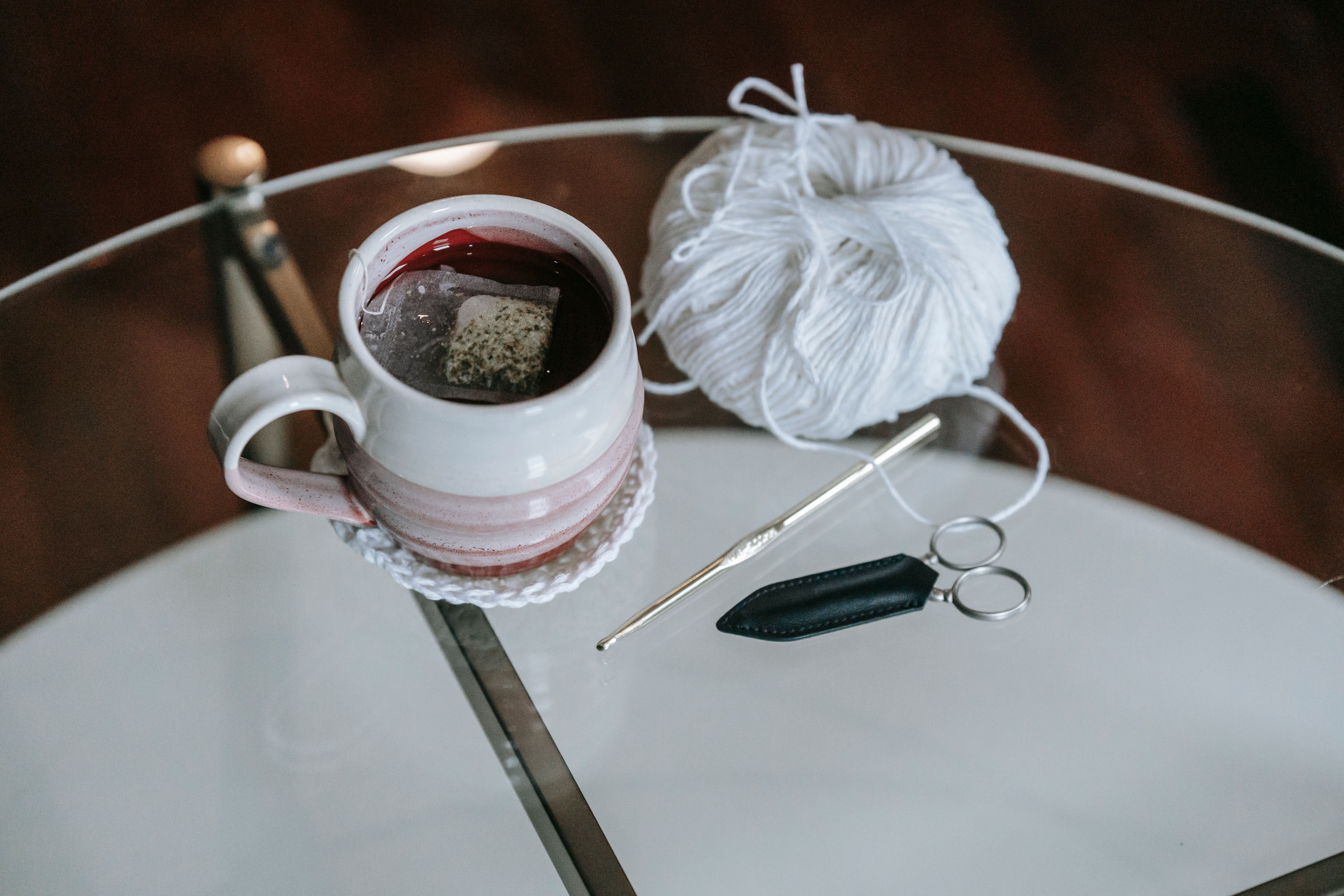 Cozy setup featuring tea and crochet materials on a glass table