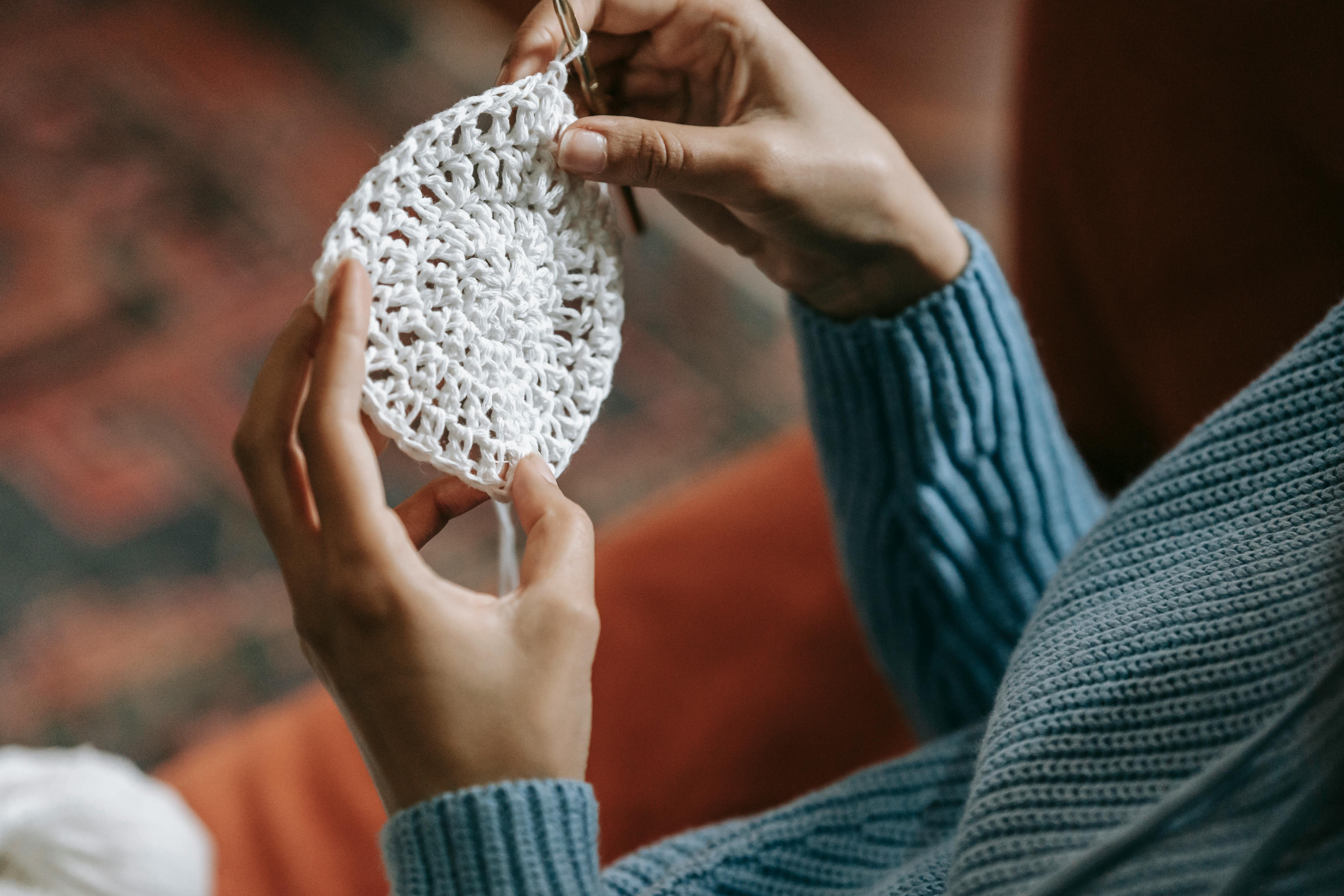 Close-up view of hands knitting a delicate white crochet pattern, highlighting the details and texture related to buy custom 