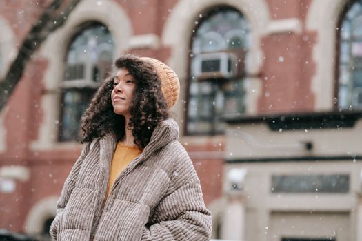 Portrait of a young woman with curly hair enjoying a snowy winter day outdoors.