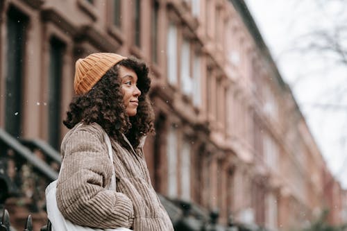 Contemplative black woman on street in snowfall