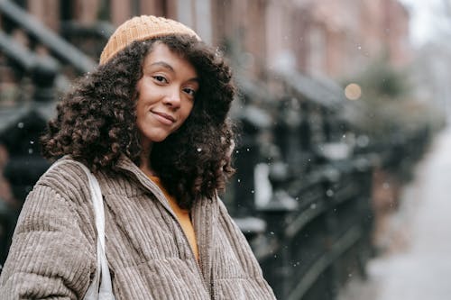 Smiling black woman in outerwear in winter town