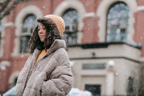 Dreamy black woman in snowfall in city