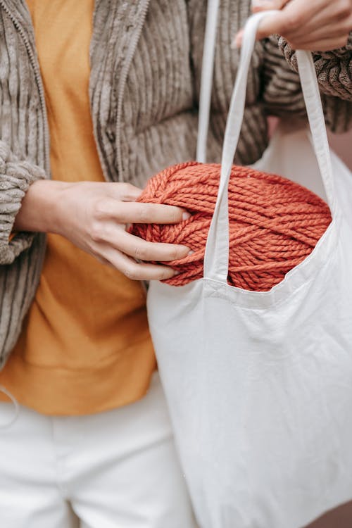 Crop craftswoman putting skein in eco bag