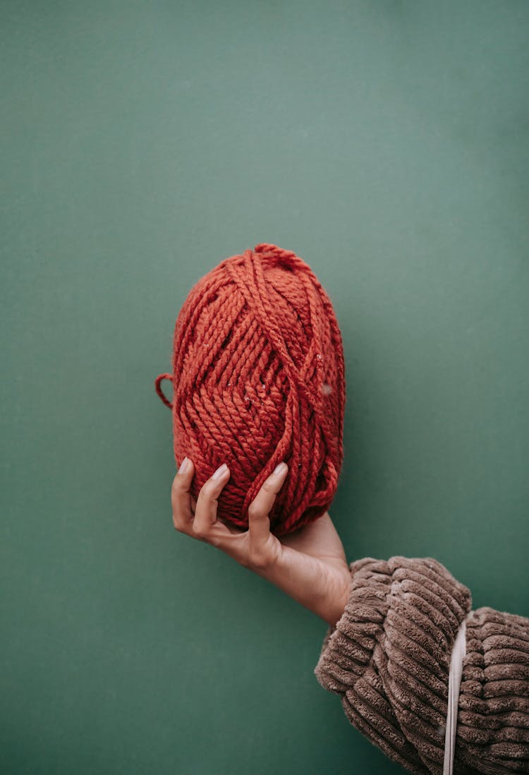 Female Reaching Out Hand With Ball Of Red Yarn