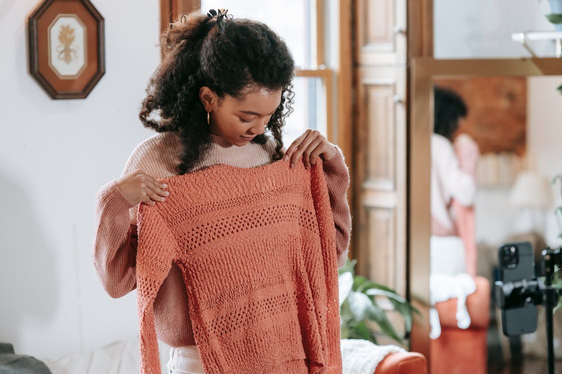 Free Black female demonstrating knitting sweater and recording video on smartphone Stock Photo