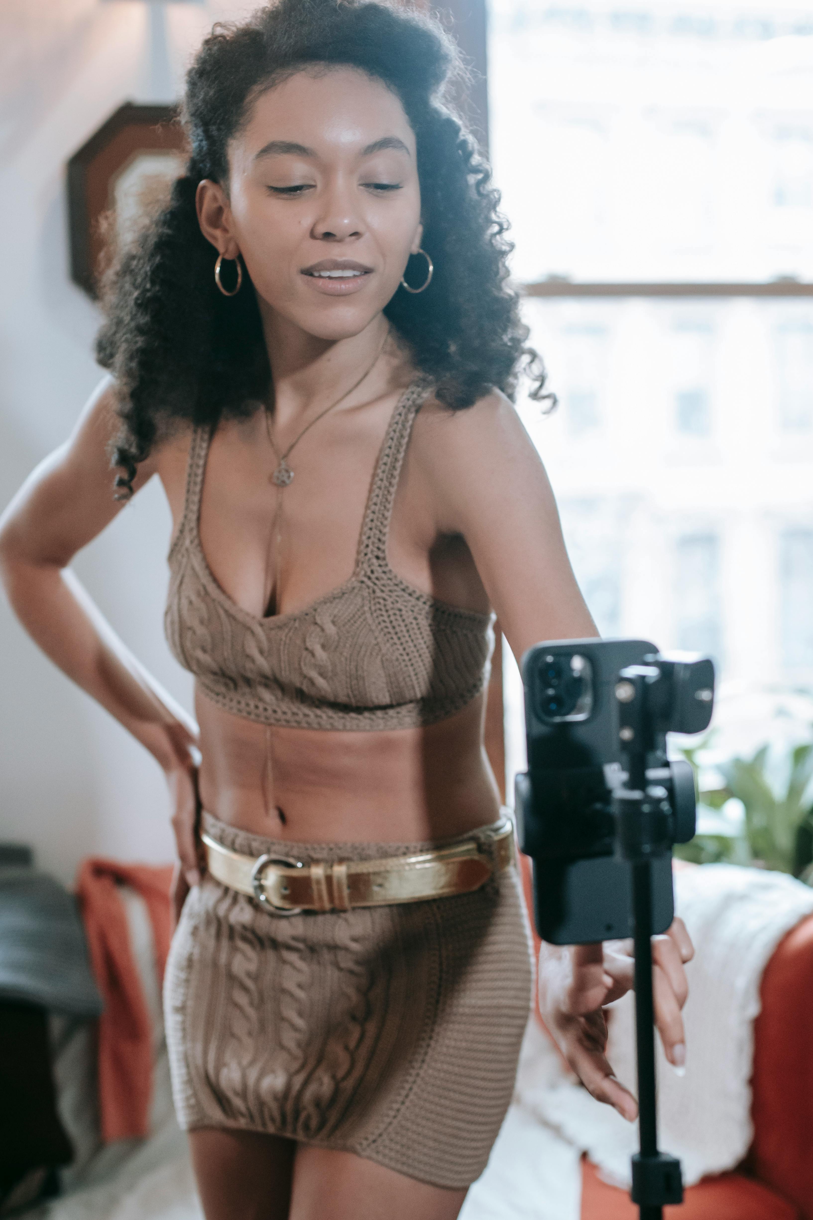 stylish black woman recording video on smartphone in light room