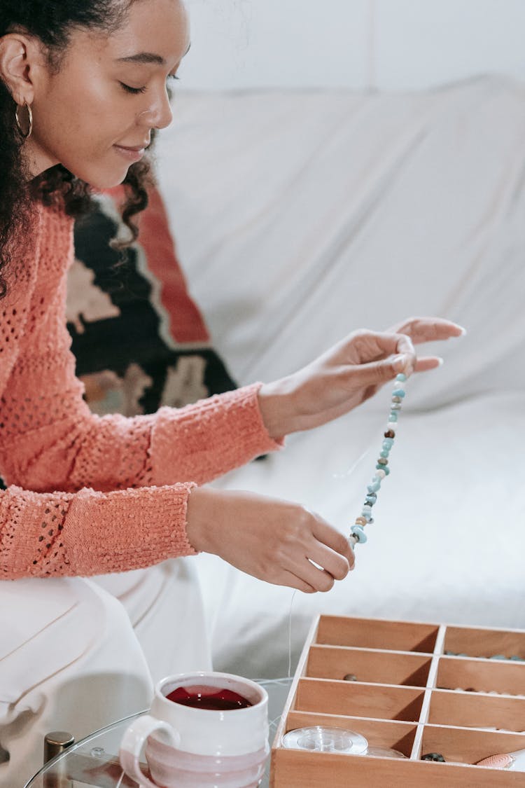 Black Woman Making Handmade Bracelet On Couch