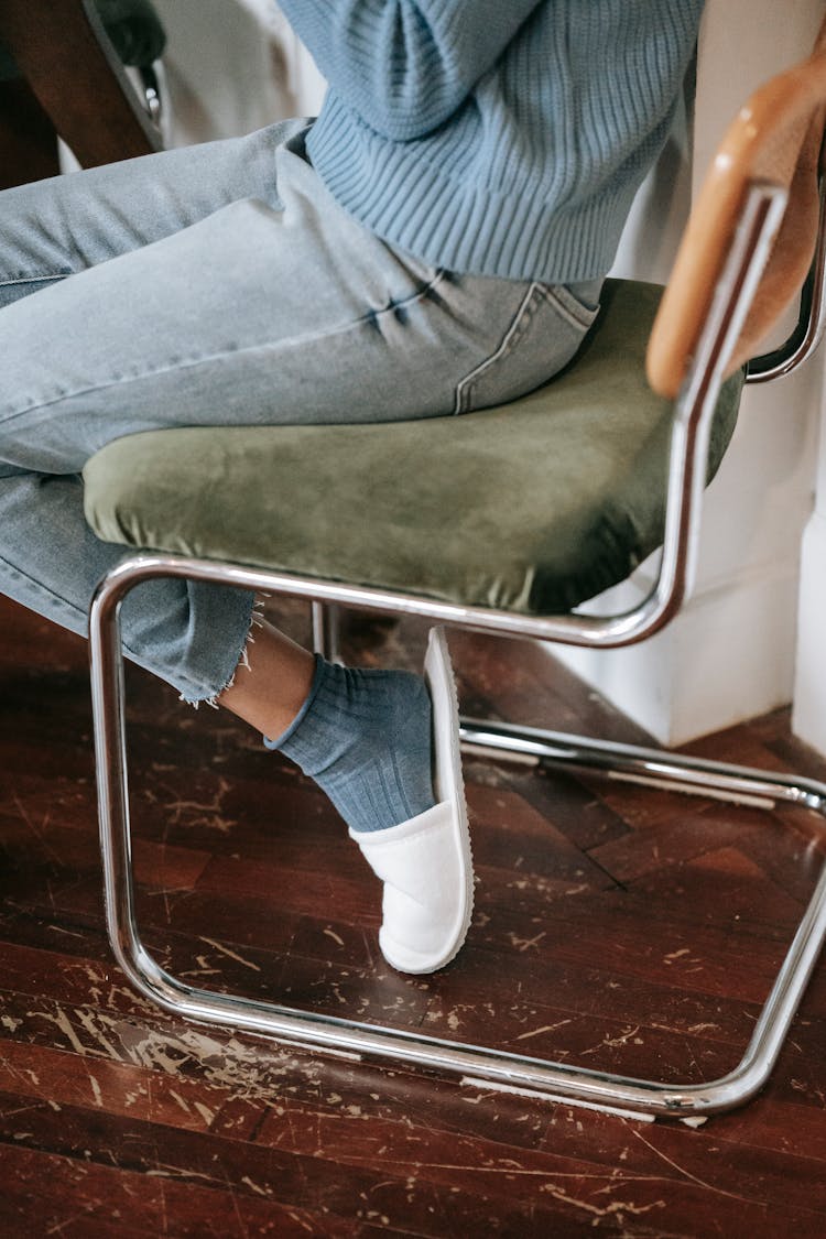 Crop Woman In Slippers Resting On Chair At Home