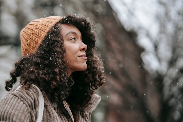 Contemplative Ethnic Woman Admiring Snowfall In City