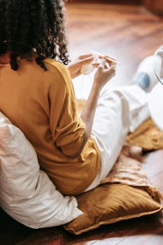 A woman with curly hair crocheting indoors, embodying relaxation and creativity.