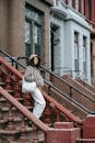 Black woman in outerwear with cloth bag on urban stairs