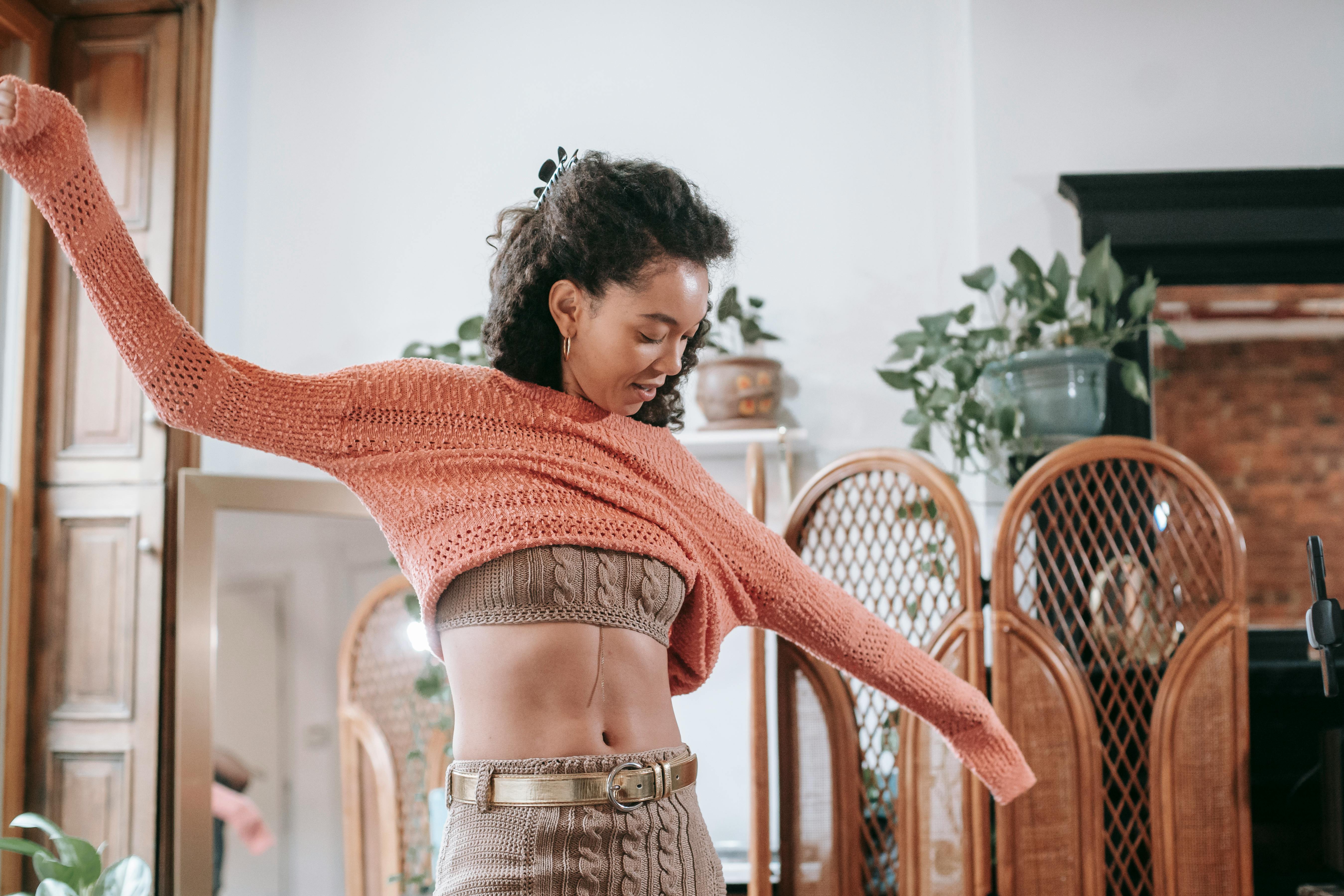 young black woman putting on light orange sweater