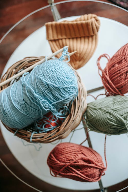 Skeins of yarn knitting needles and light orange knitted hat