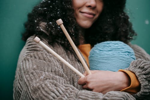 African American woman cuddling skein of yarn and knitting needles