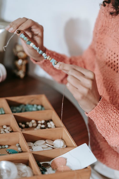 Female artisan demonstrating handmade accessory while doing beading ...