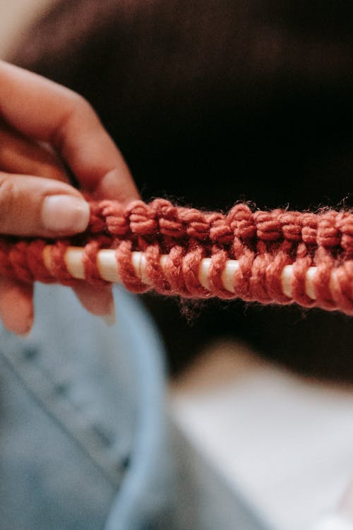 Knitted loops of woolen orange thread on wooden crochet