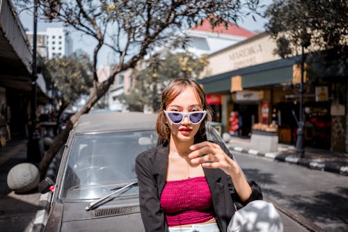 A Woman in Sunglasses Leaning on the Hood of a Car