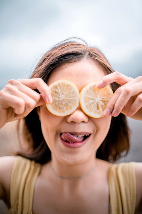 Free A Girl Covering Her Eyes with Lemon Slices Stock Photo