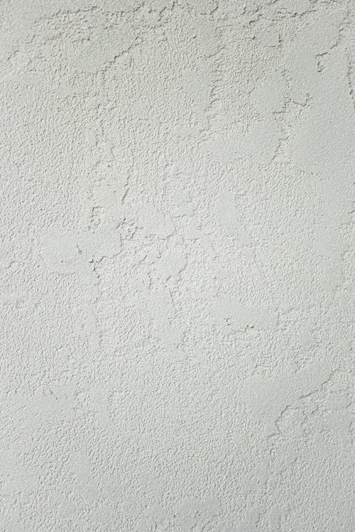 Minimalist clean background of white wall with roughness and cracks with scratches in studio in daylight