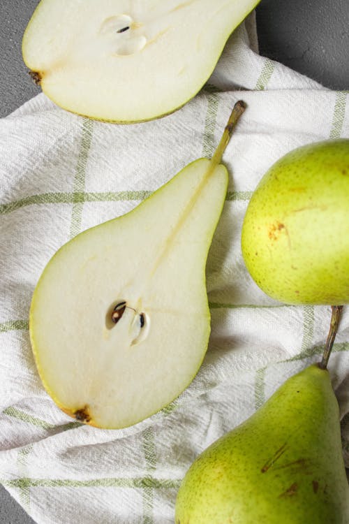 From above of fresh ripe pieces of green pears placed on white fabric on table in light place