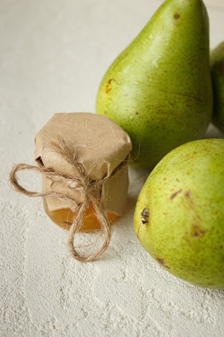 Green Pears Near Jar With Honey On Surface