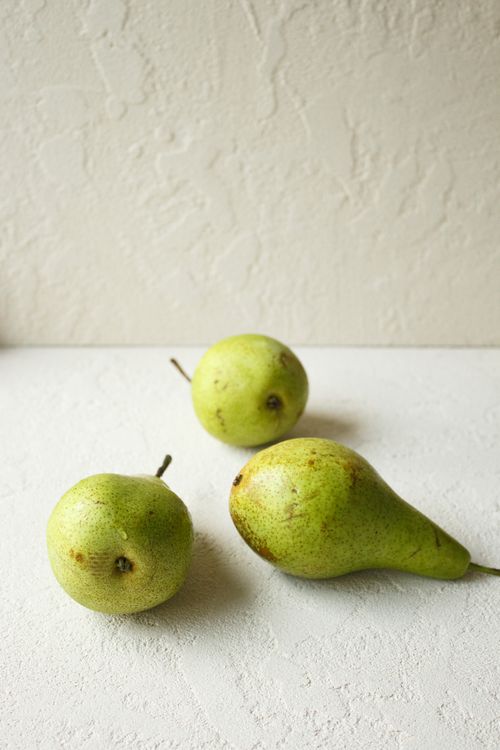 Free Three organic green pears arranged on a textured surface, capturing the essence of simplicity and nature. Stock Photo