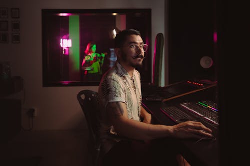 A Man Sitting Near the Audio Mixer Inside the Studio