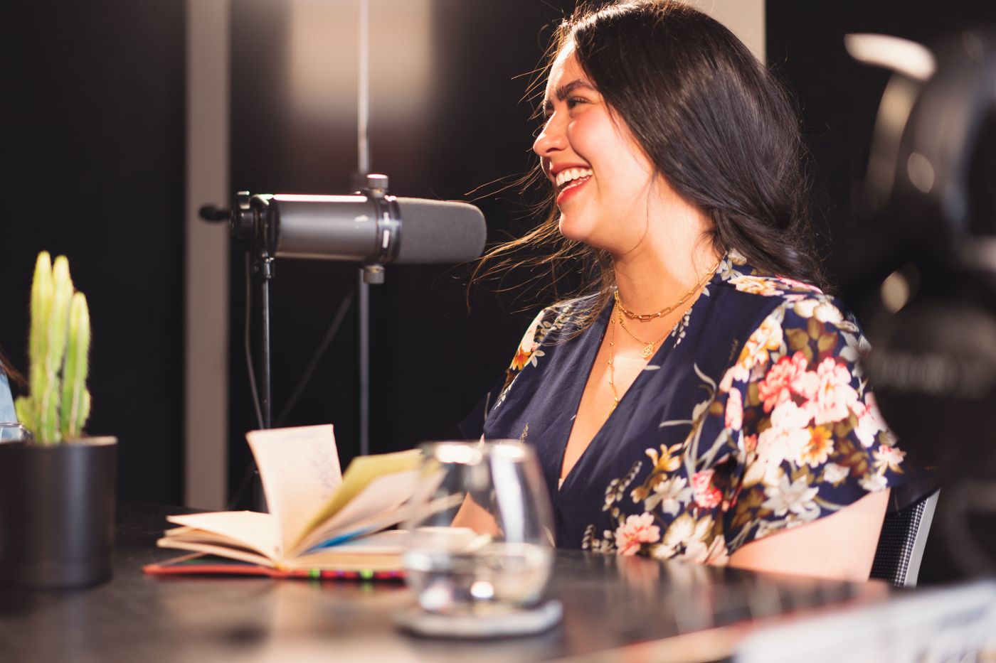 Radio host laughing at the microphone with her notes open in a professional studio