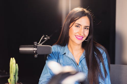 A Woman in Denim Clothes Smiling Near the Microphone