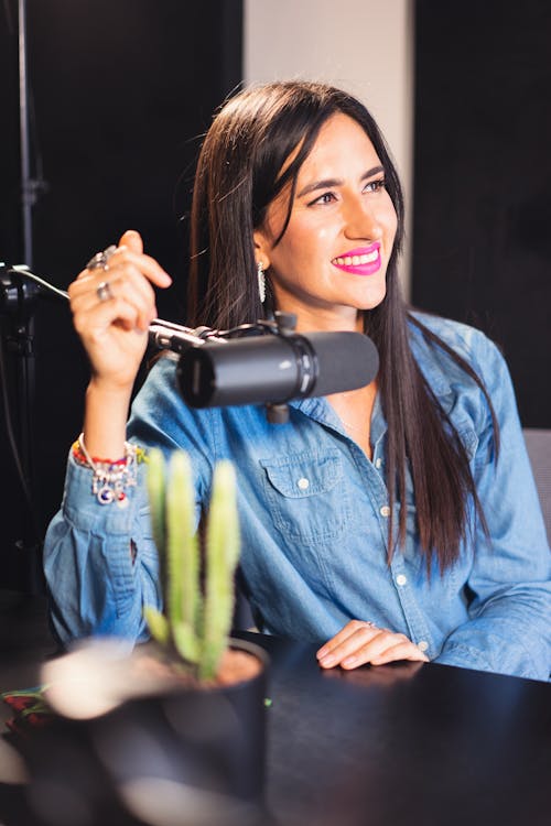 Woman in Blue Denim Button-Up Shirt Sitting Near a Microphone