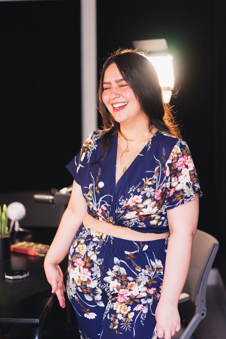 A Woman In Floral Top Laughing While Standing Near The Table