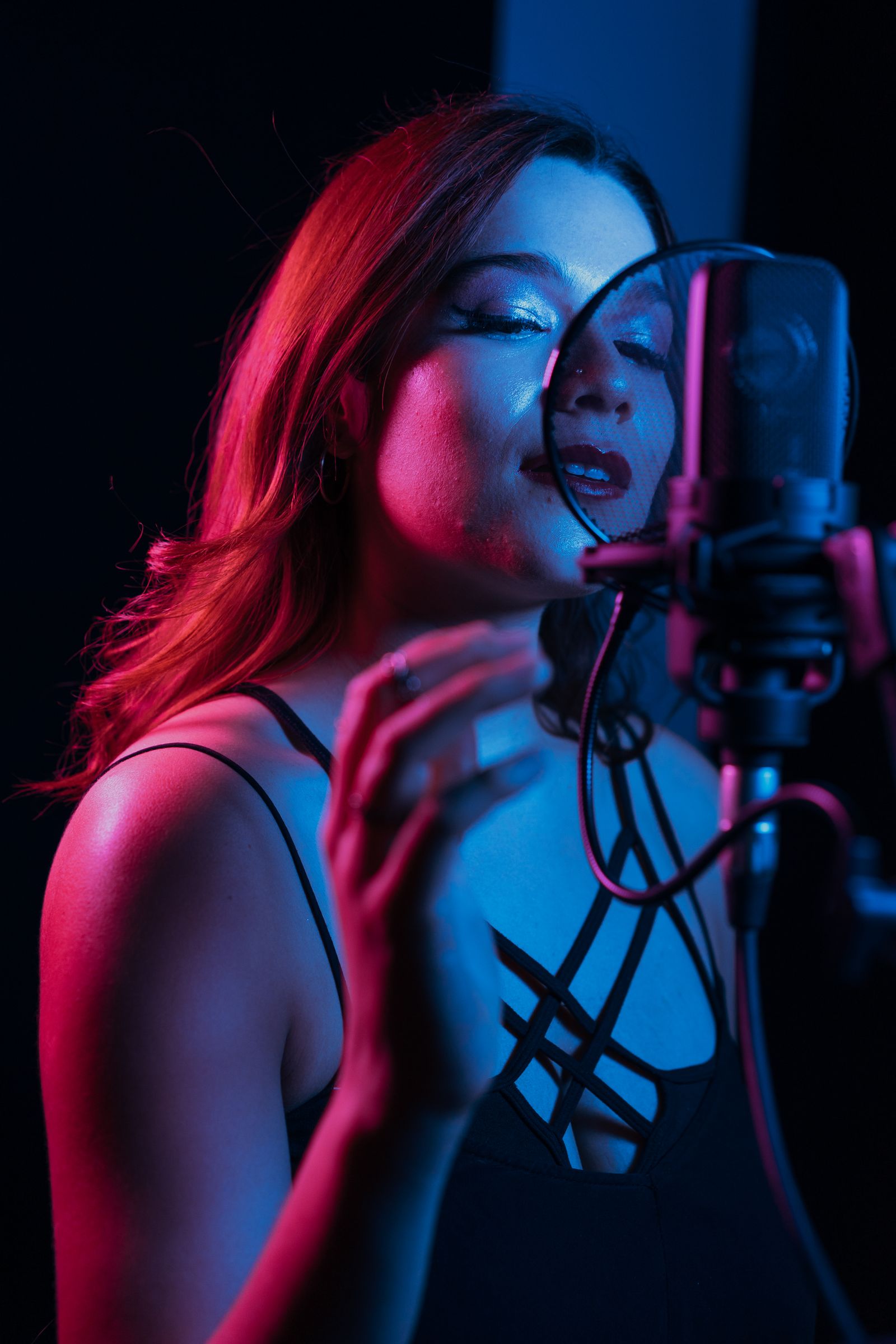 Vocalist singing into a condenser microphone under pink neon light