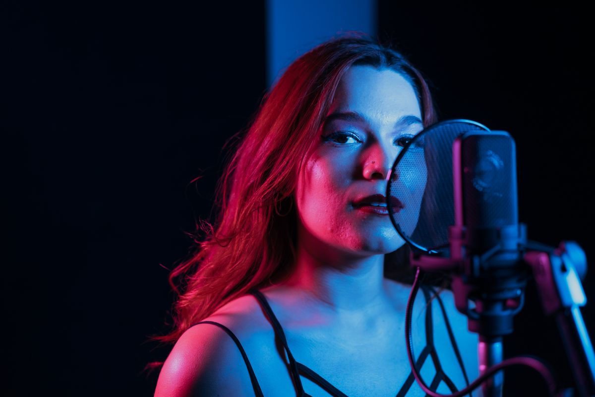 Artist recording vocals in a moody, colorfully lit studio