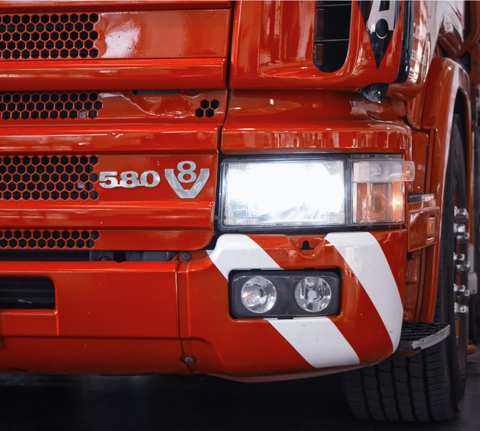 Close-up of a truck's front end showing a shining headlight and grille