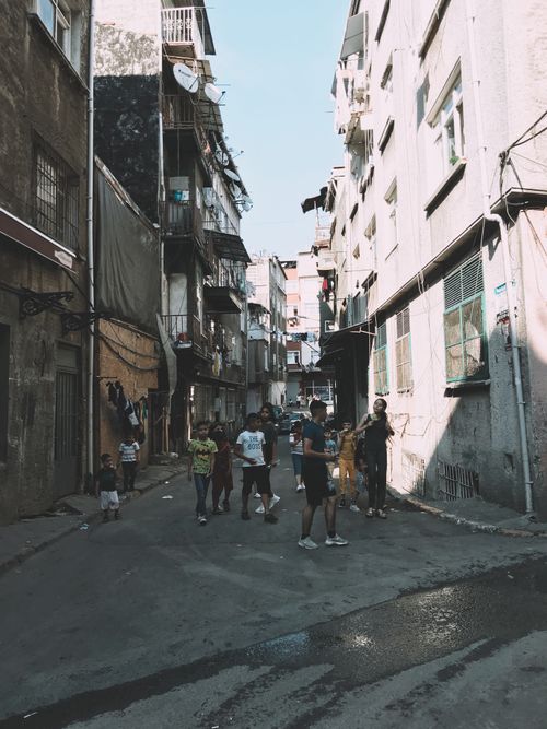 Free Crowd of local children standing on asphalt walkway near old residential houses in poor district of town on summer day Stock Photo