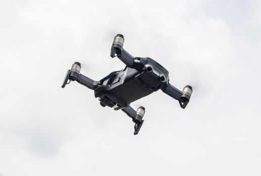 A modern drone captured while flying against a cloudy sky, showcasing innovation in technology.