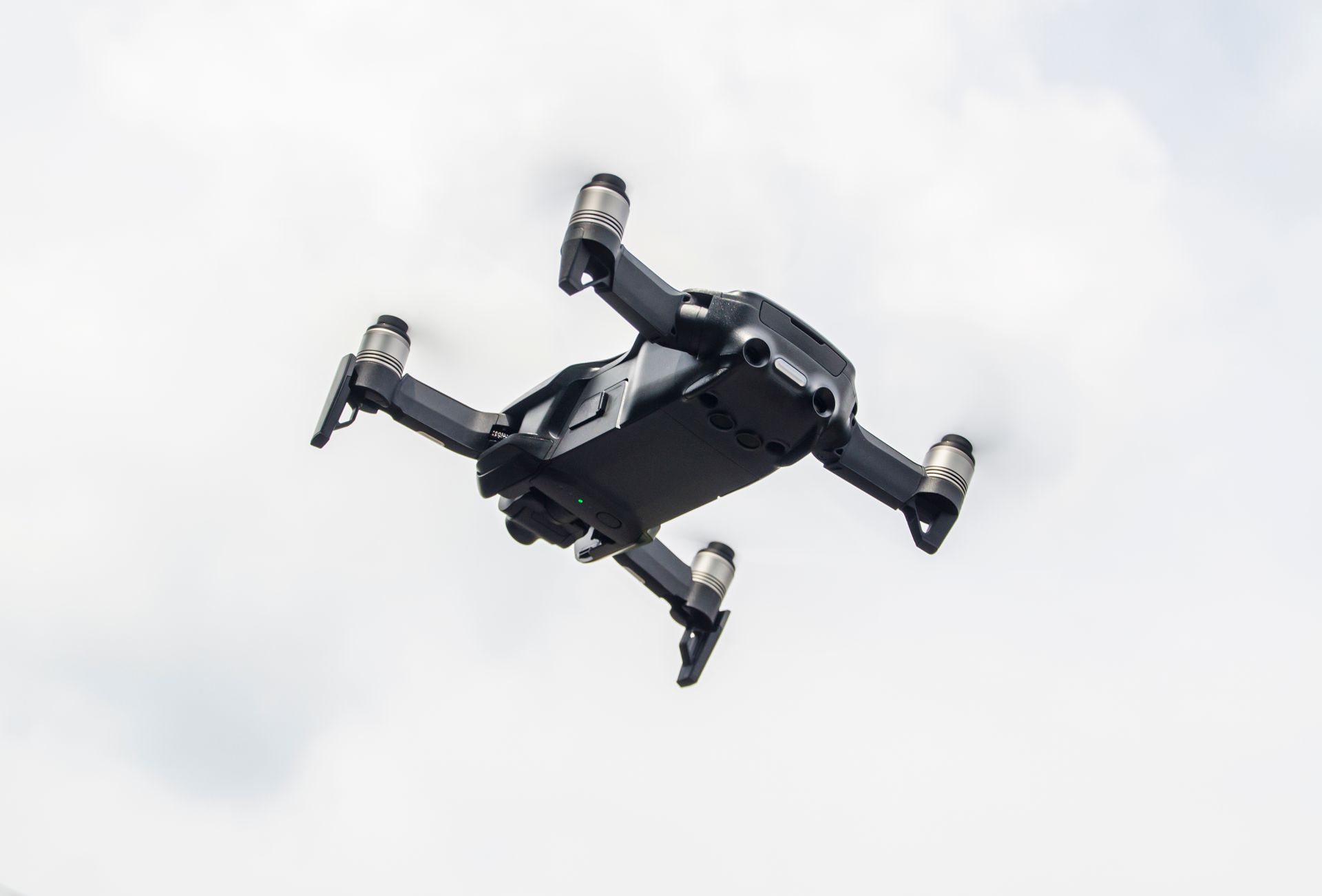 A modern drone captured while flying against a cloudy sky, showcasing innovation in technology.