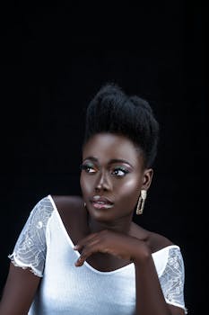 Stunning portrait of a woman with elegant earrings and vivid makeup against a dark backdrop.