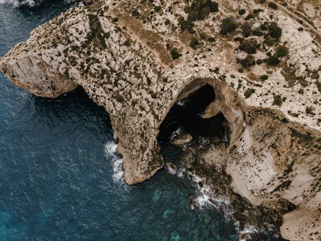 Stunning aerial view of the Blue Grotto cliffs in Malta showcasing breathtaking rock formations and clear blue waters.