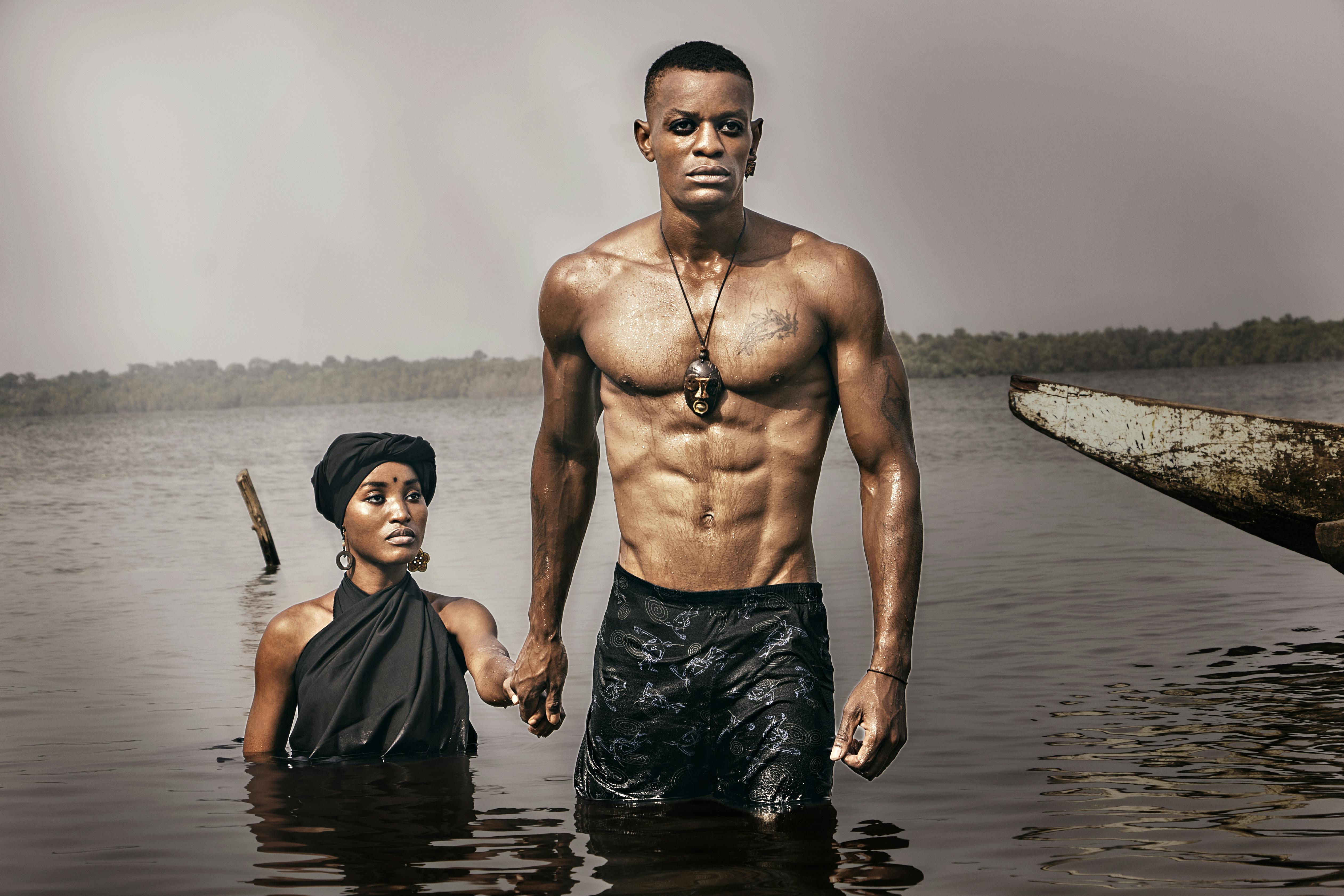 Powerful imagery of a black couple partially submerged in water, exuding strength and calm.