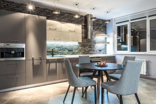 Free Stylish modern kitchen with brick wall and sleek dining area, showcasing minimalist design. Stock Photo