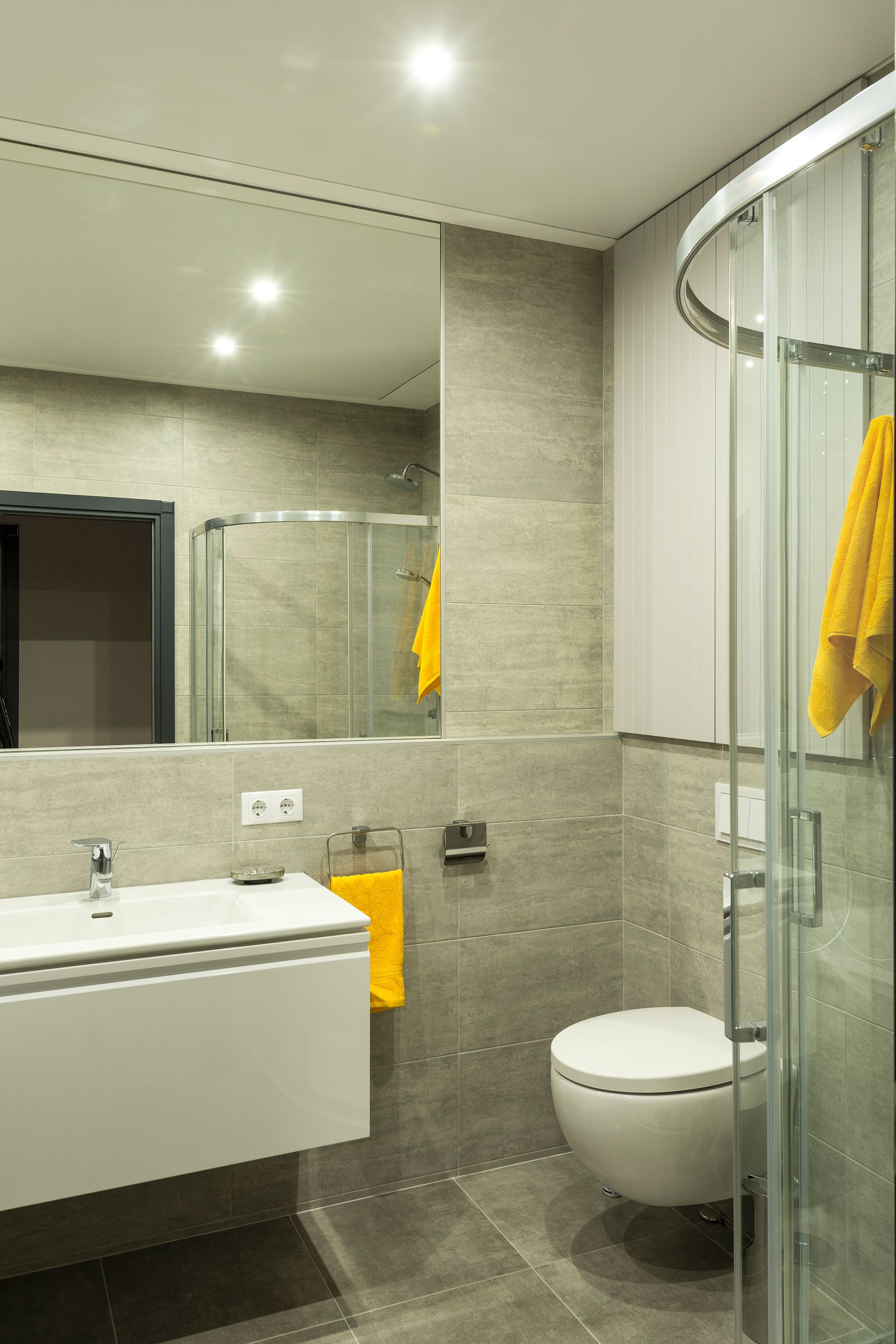 Modern neutral bathroom with repeated yellow towel accents