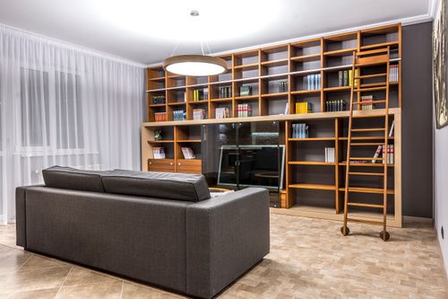 Free Stylishly designed living room featuring wooden bookshelves and a comfortable sofa. Stock Photo