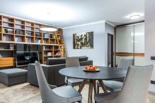 Elegant living room featuring a large bookshelf and dining table with chairs, creating a comfortable space.
