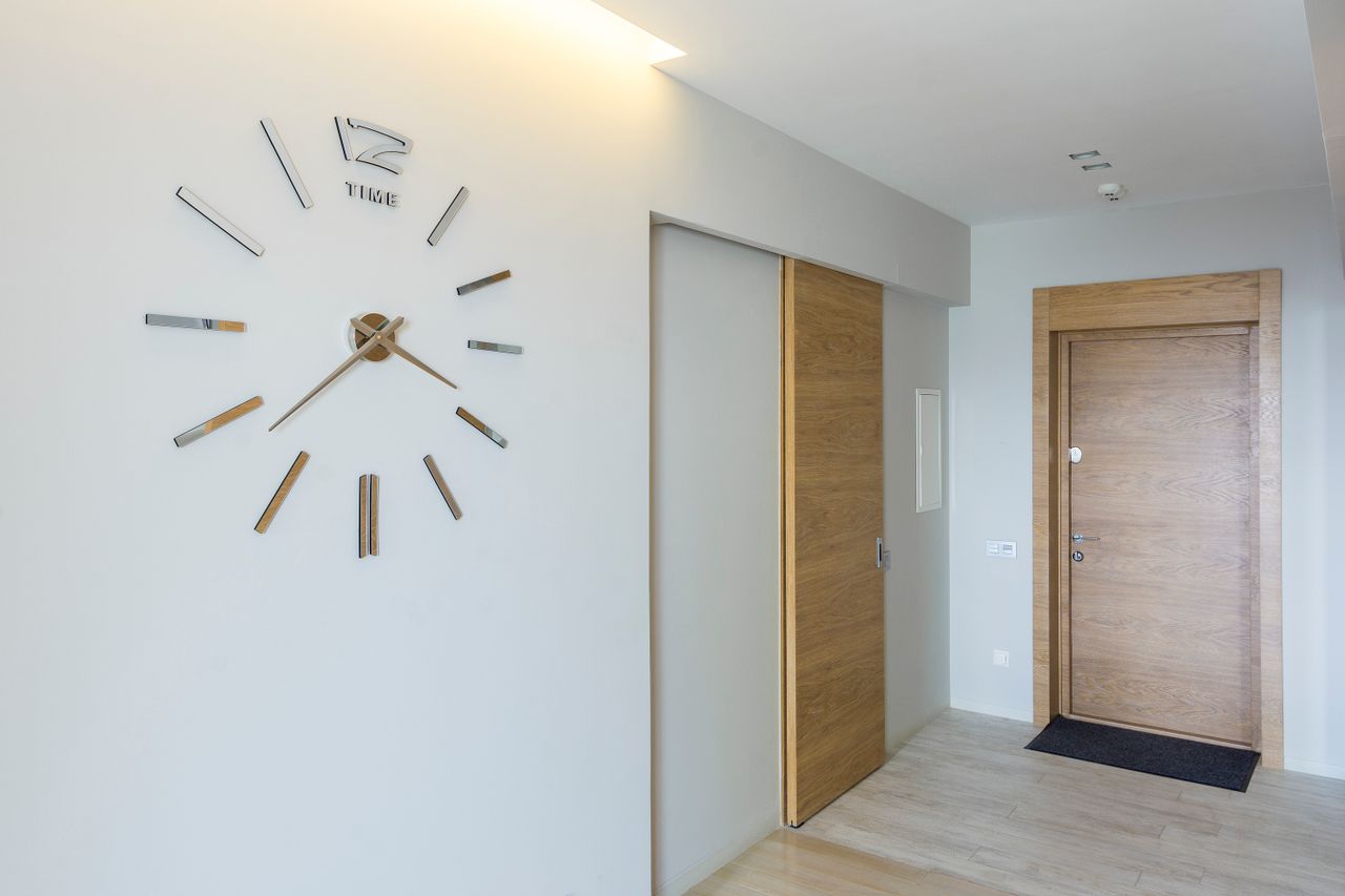 Modern hallway with a wooden sliding door tucked into the wall beside a large wall clock